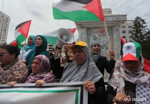 Palestinians hold placards and Palestine flags during a demonstration to calling for an end in the political division and the national reconciliation in Gaza city, on May 20, 2014. Photo by Ashraf Amra
