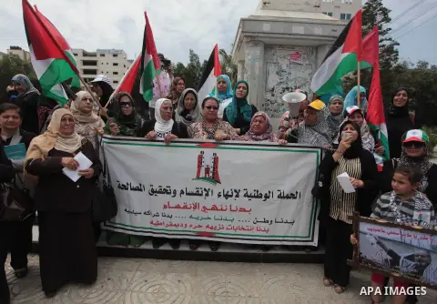 Palestinians hold placards and Palestine flags during a demonstration to calling for an end in the political division and the national reconciliation in Gaza city, on May 20, 2014. Photo by Ashraf Amra