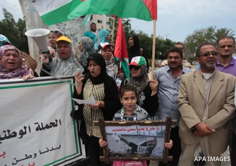 Palestinians hold placards and Palestine flags during a demonstration to calling for an end in the political division and the national reconciliation in Gaza city, on May 20, 2014. Photo by Ashraf Amra