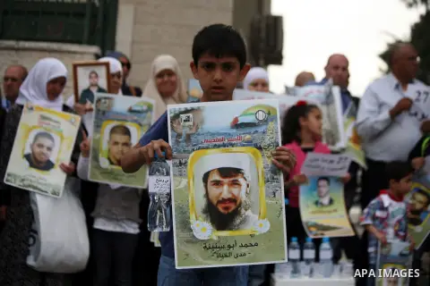 Palestinians hold placards during a protest calling for the end of administrative detention, outside the Red Cross headquarter in Jerusalem on May 20, 2014 and to express solidarity with Palestinian prisoners on hunger s...