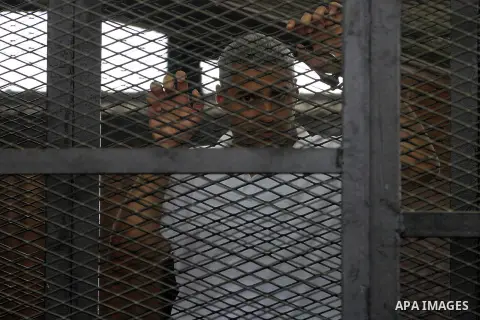 Defendants in the Marriott terror cell case in Cairo stand in cages in an Egyptian courtroom, in Cairo on May 22, 2014. A total of 20 defendants in the case are charged with harming Egypt's national interests by spreadin...