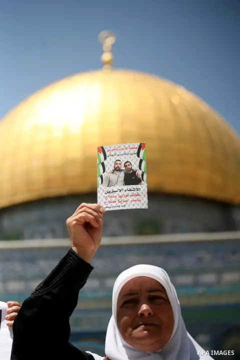A Palestinian woman holds pictures of Palestinian prisoners in Israeli jails to express solidarity with them, following Friday prayer at al-Aqsa mosque compound, in Jerusalem's Old City on May 23, 2014. In late March, Is...