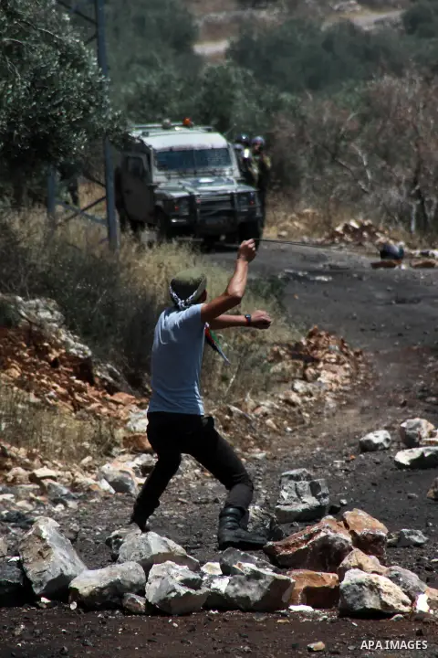 A Palestinian protester uses a slingshot to hurl stones at Israeli security forces during clashes following a weekly protest against the expropriation of Palestinian land by Israel in the West Bank village of Kfar Qaddum...