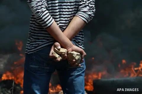 A Palestinian protester hold rocks as he prepares to throw it at Israeli security forces during clashes following a weekly protest against the expropriation of Palestinian land by Israel in the West Bank village of Kfar...