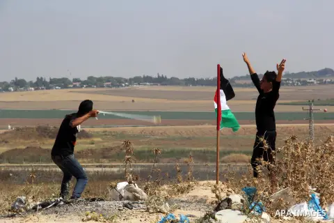A Palestinian protester uses a slingshot to hurl stones towards Israeli security forces during clashes following a protest to show solidarity with Palestinian prisoners held in Israeli jails