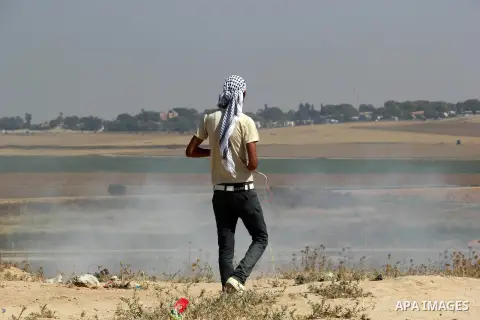 A Palestinian protester uses a slingshot to hurl stones towards Israeli security forces during clashes following a protest to show solidarity with Palestinian prisoners held in Israeli jails