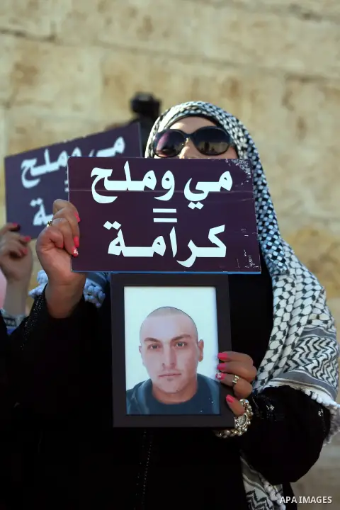 A Palestinian woman holds placard during a protest to solidarity with Palestinian prisoners held in Israeli jails, at Damascus Gate in Jerusalem's Old City on May 24, 2014. Some 120 Palestinians jailed without trial in I...
