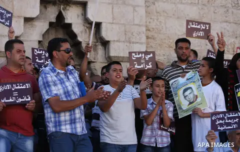 Palestinian protesters hold placards during a protest to solidarity with Palestinian prisoners held in Israeli jails, at Damascus Gate in Jerusalem's Old City on May 24, 2014. Some 120 Palestinians jailed without trial i...