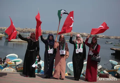 Palestinians hold a Turkish flag as activists ride a boat during a rally ahead of the 4th anniversary of the Mavi Marmara Gaza flotilla incident, at the seaport of Gaza City May 29, 2014. Nine activists, eight Turkish an...