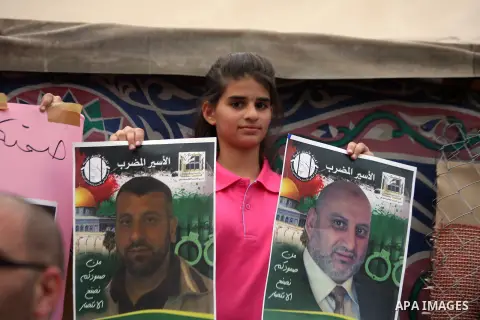 A Palestinian girl holds pictures for the Palestinian prisoners during a protest, in the East Jerusalem neighborhood of Silwan on May 29, 2014. It was about 120 Palestinians imprisoned without trial in Israel on an open...