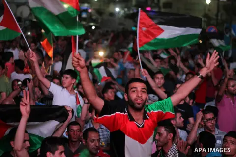 Palestinians celebrate in the West Bank city of Ramallah on May 30, 2014, after Palestine qualified for their maiden Asian Cup appearance with a 1-0 win over injury-hit Philippines in the final of the AFC Challenge Cup i...