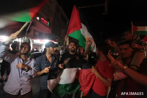 Palestinians celebrate in Gaza City on May 30, 2014, after Palestine qualified for their maiden Asian Cup appearance with a 1-0 win over injury-hit Philippines in the final of the AFC Challenge Cup in Maldives. Photo by...