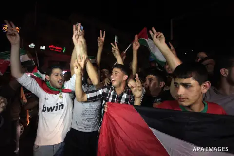 Palestinians celebrate in Gaza City on May 30, 2014, after Palestine qualified for their maiden Asian Cup appearance with a 1-0 win over injury-hit Philippines in the final of the AFC Challenge Cup in Maldives. Photo by...