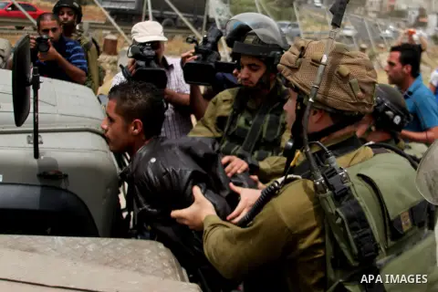 Israeli soldiers detain a Palestinian boy during a protest in support of Palestinian prisoners on hunger strike in Israeli jails at the al-Aroub Palestinian refugee camp, just north the West Bank town of Hebron on May 31...