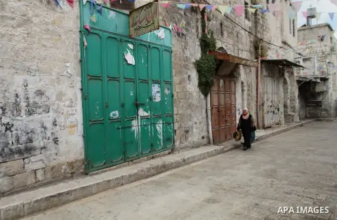 A Palestinian woman walks past a closed shop during a strike to solidarity with Palestinian prisoners on hunger strike held in Israeli jails, in the West Bank city of Nablus on June 1, 2014. Photo by Nedal Eshtayah