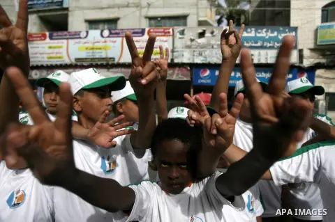 Palestinian children who participate in a summer camp organized by Hamas, flash victory signs as they parade the streets during a rally to show solidarity with Palestinian prisoners held in Israeli jails, in Rafah in the...