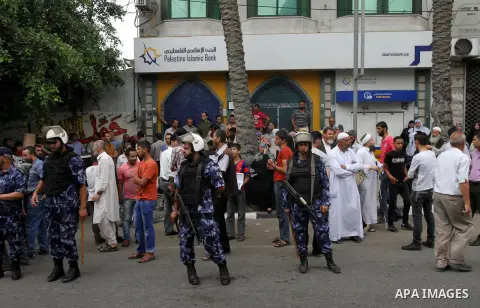Palestinian employees paid by Palestinian Authority stand outside the Palestine Islamic Bank as they wait to receive their salaries, in Gaza city on June 5, 2014. A Palestinian unity government formed by President Mahmou...