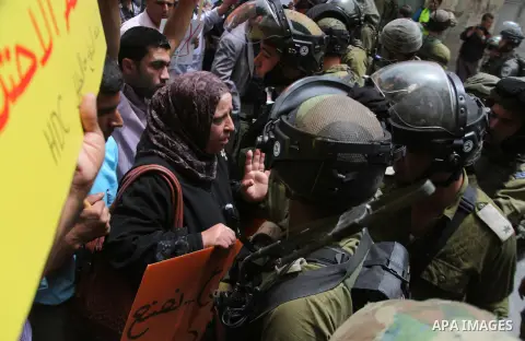A Palestinian woman argues with an Israeli army soldier during a protest in solidarity with prisoners on hunger strike, in the West Bank city of Hebron June 5, 2014. Some 120 Palestinians jailed without trial in Israel h...