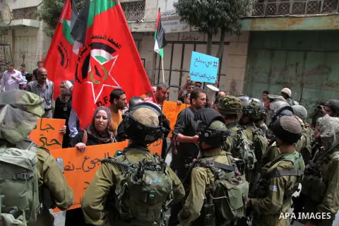 Palestinian protesters hold a sign in front of Israeli troops during a protest in solidarity with prisoners on hunger strike, in the West Bank city of Hebron June 5, 2014. Some 120 Palestinians jailed without trial in Is...