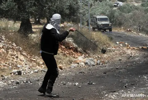 A Palestinian protester uses slingshots to hurl stones at Israeli security forces during clashes following a weekly protest against the expropriation of Palestinian land by Israel in the West Bank village of Kfar Qaddum,...