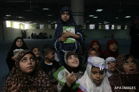 Palestinian girls read verses from the Quran during a summer camp for the study of Islam's holy book organized by the Islamist movement Hamas in Rafah in the southern Gaza Strip on June 7, 2014. Photo by Eyad Al Baba
