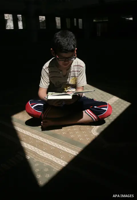 A Palestinian boy reads verses from the Quran during a summer camp for the study of Islam's holy book organized by the Islamist movement Hamas in Rafah in the southern Gaza Strip on June 7, 2014. Photo by Eyad Al Baba
