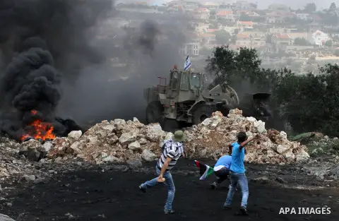 Palestinian protesters throw stones at an Israeli bulldozer during clashes following a weekly protest against the expropriation of Palestinian land by Israel in the West Bank village of Kfar Qaddum, near Nablus on June 1...