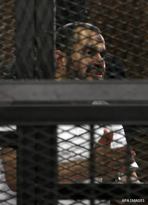 Egyptian Muslim Brotherhood members stand inside the defendants cage during their trial in the capital Cairo on June 17, 2014. The court postponed to July 23 the verdict in the trial of Muslim Brotherhood Supreme Guide M...