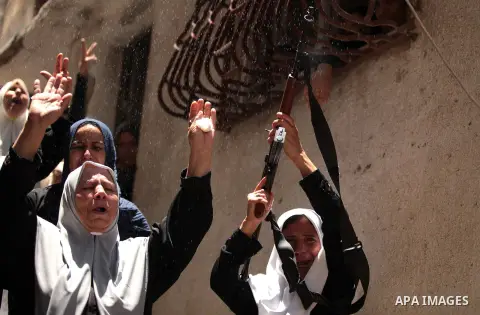 A relative of Palestinian member of Hamas' armed wing Ibraheem al-Arqan holds a weapon as others mourn during his funeral in Gaza City June 21, 2014. Hamas' armed wing in Gaza said at least six members of its group, one...