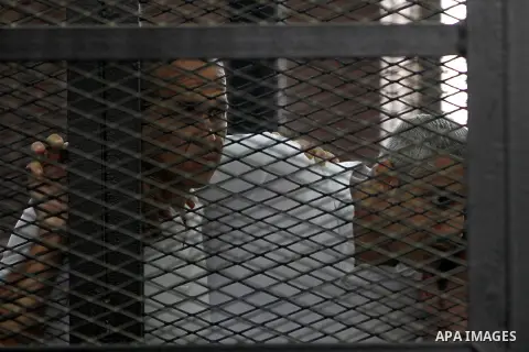 Australian journalist Peter Greste and Mohamed Fahmy stand inside court's cage as he waits to listen the ruling at a court in Cairo June 23, 2014. Three Al Jazeera journalists were jailed for seven years in Egypt on Mond...