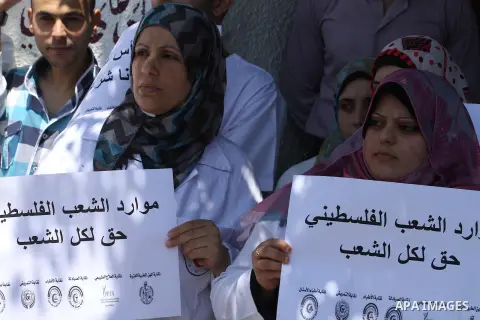 Palestinian Doctors of the formerly Hamas-run government in the Gaza Strip hold banners during a protest to demanding their salaries, in Gaza city, on June 24, 2014. The union of public sector employees in Gaza threatene...