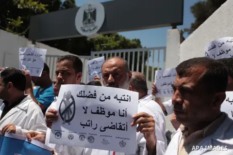 Palestinian Doctors of the formerly Hamas-run government in the Gaza Strip hold banners during a protest to demanding their salaries, in Gaza city, on June 24, 2014. The union of public sector employees in Gaza threatene...