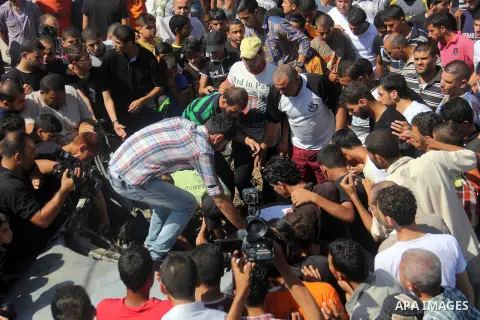 Palestinians gather around a car that was targeted by an Israeli air strike in Gaza City on June 27, 2014. The air strike killed two Palestinians, medics said, hours after a bomb exploded near troops manning Israel's sec...