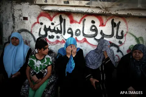 Palestinian relatives of Osama al-Hosomi mourn during his funeral outside his family's house in the northern Gaza Strip June 27, 2014. An Israeli air strike killed two Palestinian militants, one of them al-Hosomi, and cr...