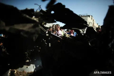 Palestinians inspect a car that was targeted in an Israeli air strike in Gaza City on June 27, 2014. An Israeli air strike killed two Palestinian militants and critically wounded a third in the Gaza Strip on Friday, the...