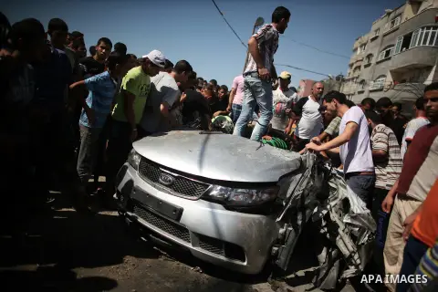 Palestinians inspect a car that was targeted in an Israeli air strike in Gaza City on June 27, 2014. An Israeli air strike killed two Palestinian militants and critically wounded a third in the Gaza Strip on Friday, the...