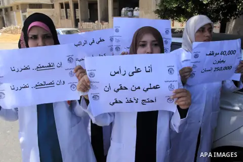 Palestinian employees of the health ministry hold placards during a protest against not receiving their salaries, in Gaza City on June 30, 2014. Many issues involving the Strip, such as the fate of former employees of th...