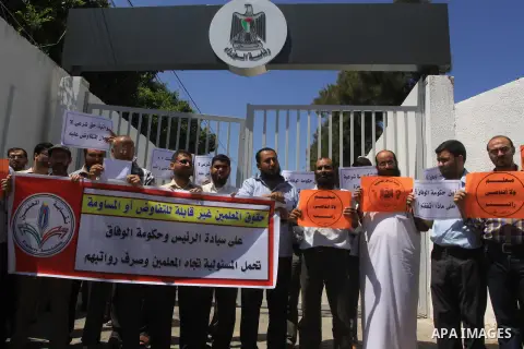 Palestinian Teachers hold placards during a protest against not receiving their salaries, in Gaza City on July 01, 2014. Many issues involving the Strip, such as the fate of former employees of the Hamas government, have...