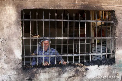 A Palestinian man inspects his home and a sheep farm after an attacked by Israeli settlers in the village of Aqraba southern the West Bank city of Nablus, on July 2, 2014. Israeli settlers write the words "blood vengeanc...
