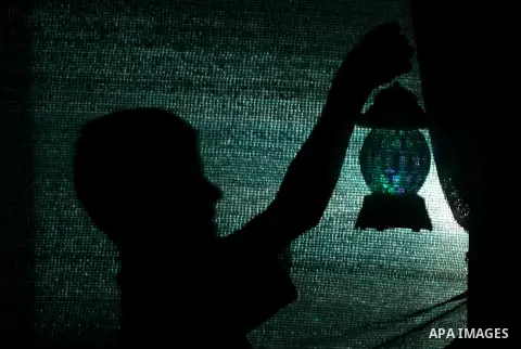 A Palestinian boy is seen behind a curtain holding a lantern behind on the third day of the Muslim fasting month of Ramadan, in Rafah in the southern Gaza Strip, on July 1, 2014. Muslims around the world celebrate Ramada...