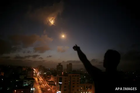 A flare illuminates the sky following an Israel airstrike over Gaza City early on July 3, 2014 as Israeli warplanes launched early morning airstrikes on different targets in the Gaza Strip, including sites belonging to H...