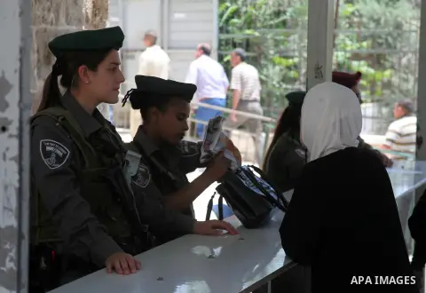 An Israeli police officer searches the bag of a Palestinian woman before reach the Ibrahimi mosque "Sanctuary of Abraham" to the traditional Friday prayers, the first of Islam's holy month of Ramadan, in the West Bank Ci...