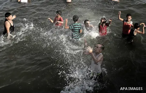 Palestinian boys swim in the port in Gaza City on July 6, 2014. Israel decided on July 6, 2014 to reduce the fishing zone open for Gaza fishermen from 6 nautical miles to 3 (5.6 km). Photo by Ezz Zanoun