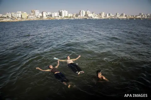 Palestinian boys swim in the port in Gaza City on July 6, 2014. Israel decided on July 6, 2014 to reduce the fishing zone open for Gaza fishermen from 6 nautical miles to 3 (5.6 km). Photo by Ezz Zanoun
