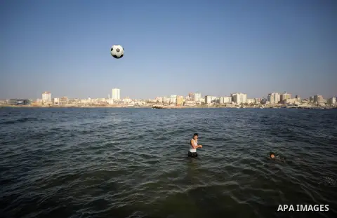 A Palestinian boy plays football as he swims in the port in Gaza City on July 6, 2014. Israel decided on July 6, 2014 to reduce the fishing zone open for Gaza fishermen from 6 nautical miles to 3 (5.6 km)). Photo by Ezz...