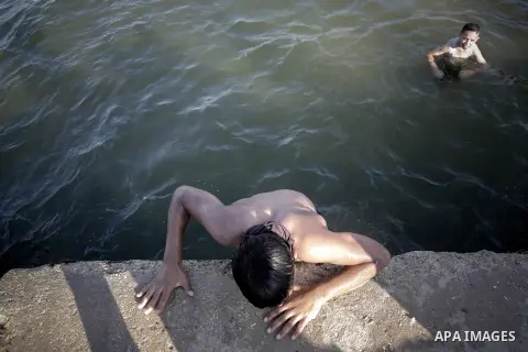 Palestinian boys swim in the port in Gaza City on July 6, 2014. Israel decided on July 6, 2014 to reduce the fishing zone open for Gaza fishermen from 6 nautical miles to 3 (5.6 km). Photo by Ezz Zanoun