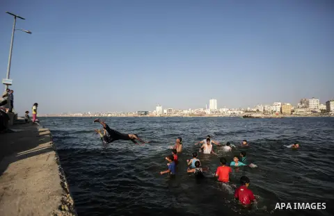 A Palestinian boy jumps into the water in the port in Gaza City on July 6, 2014. Israel decided on July 6, 2014 to reduce the fishing zone open for Gaza fishermen from 6 nautical miles to 3 (5.6 km). Photo by Ezz Zanoun