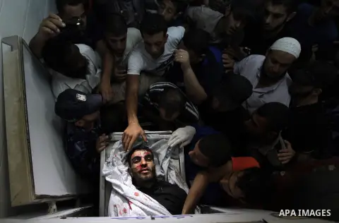 People mourn around the body of a Palestinian militant at a hospital morgue in Deir al-Balah in the central Gaza Strip July 6, 2014. Tensions were high along the Gaza border where Israel killed two Palestinian militants...