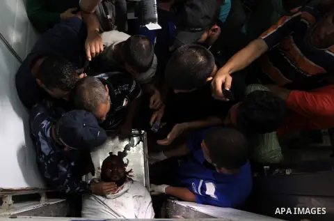 People mourn around the body of a Palestinian militant at a hospital morgue in Deir al-Balah in the central Gaza Strip July 6, 2014. Tensions were high along the Gaza border where Israel killed two Palestinian militants...
