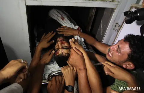 People mourn around the body of a Palestinian militant at a hospital morgue in Deir al-Balah in the central Gaza Strip July 6, 2014. Tensions were high along the Gaza border where Israel killed two Palestinian militants...